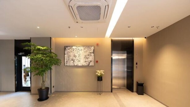 A modern lobby with a potted plant, a wall-mounted artwork, and a trash bin. - Homeinn Hotel · neo (Suzhou University Pingjiang Street) (Suzhou)