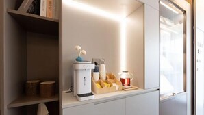 A modern kitchen with a built-in coffee machine, a tea kettle, and a stack of plates on a countertop. - Homeinn Hotel · neo (Suzhou University Pingjiang Street) (Suzhou)