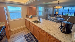 A kitchen with a large island, wooden cabinets, and a view of the ocean.
