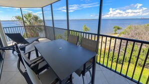 A balcony with a table and chairs, overlooking a body of water and distant land.