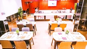 Ein Restaurant mit mehreren Tischen, Stühlen und einer Theke mit einem Fernsehbildschirm.