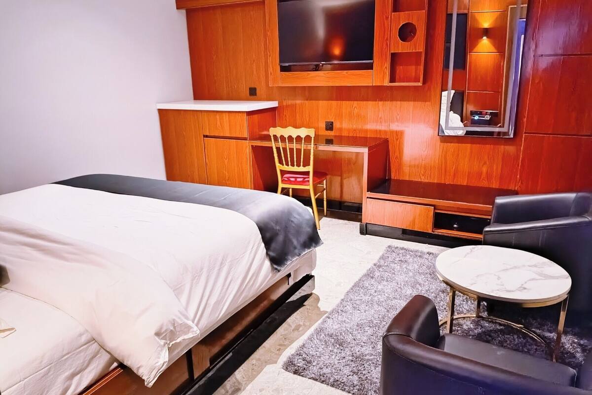Une chambre d’hôtel équipée d’un lit, d’un bureau, d’une chaise, d’une télévision et d’une petite table.