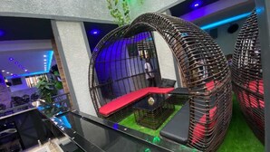 Ein modernes Interieur mit Glastrennwand, einer rot gepolsterten Bank und einer ungewöhnlichen, kugelförmigen Sitzgelegenheit.