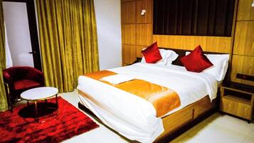 A hotel room with a large bed, a red armchair, a small round table, and a red rug.