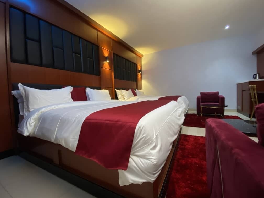 A hotel room with a large bed, a red carpet, and a red armchair.