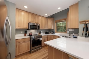 A modern kitchen with wooden cabinets, stainless steel appliances, and a large island with a sink.