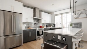 Une cuisine moderne dotée d’appareils électroménagers en acier inoxydable, d’un grand îlot central et offrant une vue sur l’extérieur.