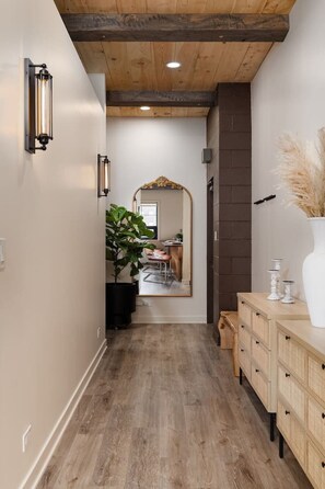A hallway with wooden flooring, a mirror, a potted plant, and a wooden cabinet with drawers. - Pine Beam Sloth Apartment next to Blue Line (Chicago)