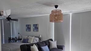A modern living room with a dark sofa, a coffee table, and a ceiling fan. - Condado Beach Condo - Fast Wi-Fi, AC, Pool & Security 24/7 (San Juan)