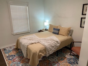 A bedroom with a bed, a nightstand, a lamp, and a chair. - Maxine's Place- A Wonderful Family Legacy (Abilene)