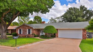 A two-story brick house with a garage, a well-maintained lawn, and a mature tree. - Maxine's Place- A Wonderful Family Legacy (Abilene)
