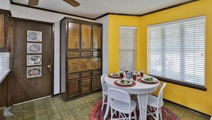 A dining area with a round table, white chairs, and a ceiling fan. - Maxine's Place- A Wonderful Family Legacy (Abilene)