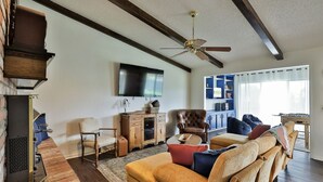 A living room with a fireplace, a sofa set, a television, and a ceiling fan. - Maxine's Place- A Wonderful Family Legacy (Abilene)