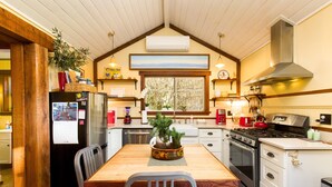 Une cuisine avec une table en bois, des chaises, un réfrigérateur, une cuisinière, un four et une fenêtre donnant sur un beau paysage.