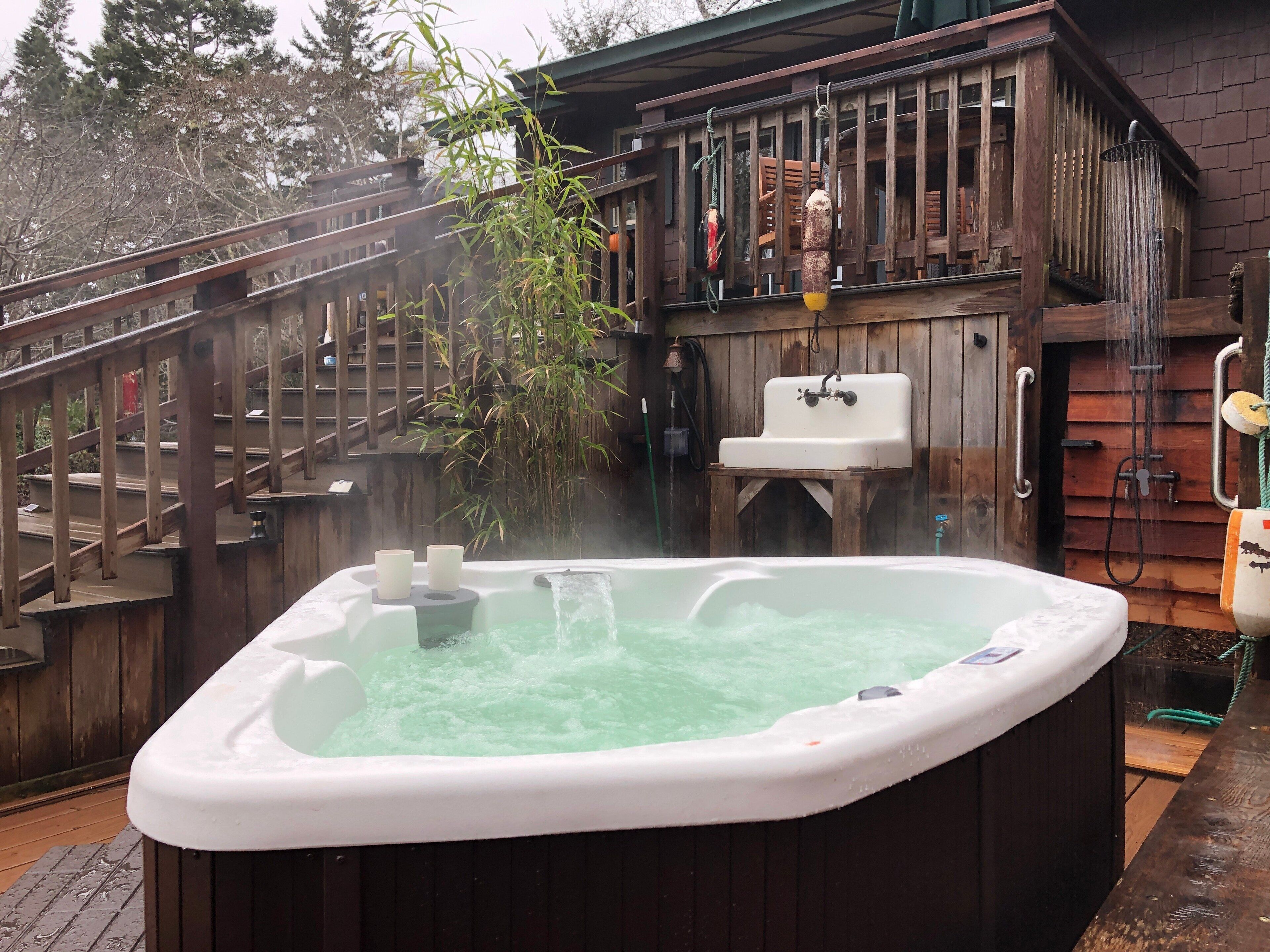 A hot tub with a wooden deck and a wooden cabin in the background.
