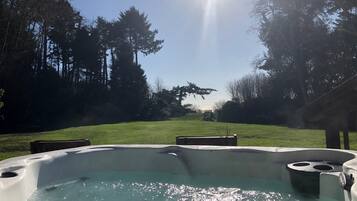 Ein Whirlpool in einem Garten mit Rasen und Bäumen.