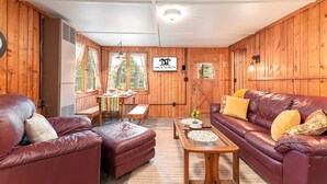 Una habitación con paneles de madera, un sofá de cuero, una mesa de madera y un banco.
