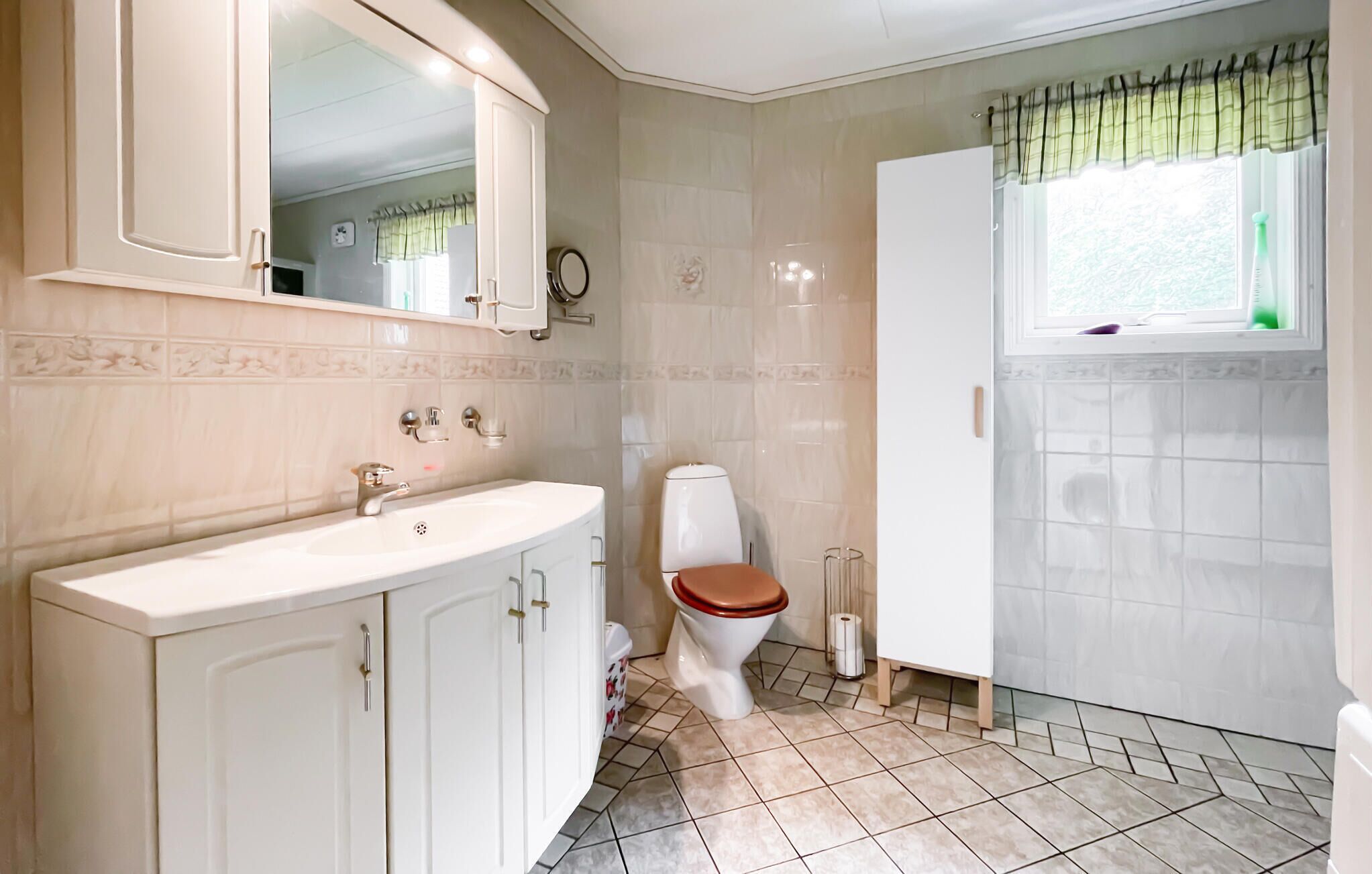 Un baño con lavamanos blanco, inodoro y un armario.