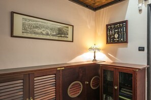 A wooden cabinet with circular cutouts, a framed historical illustration, and a decorative lamp. - GuestHost - Genoa Fine Arts Center Chic Mini Studio x2 (Genova)