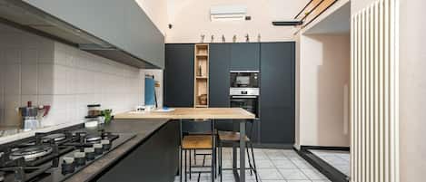 A modern kitchen with a central island, a built-in oven, and a gas stove.