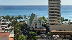 A coastal view with a prominent church, a tall hotel building, and a clear blue sky. - Ocean-view lanai, 1 block to Waikiki Beach (Honolulu)