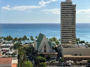 Vista costeira com uma igreja imponente, um edifício alto de hotel e um céu azul límpido.