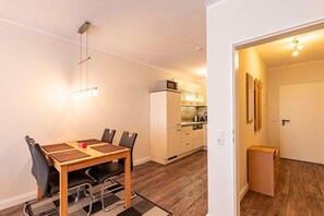 Eine moderne Wohnung mit Essbereich, Küchenzeile und einem Flur, der zu einer Tür führt.