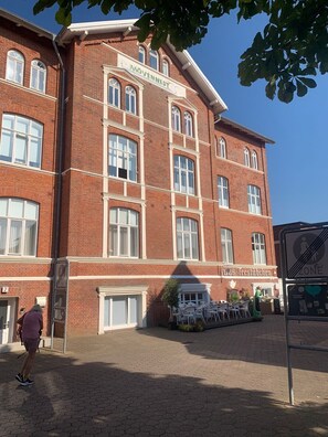 Ein rot backengebautes Gebäude mit vielen Fenstern und einem Schild mit der Aufschrift 'Mövennest'.