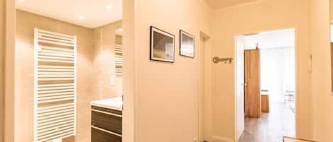 A hallway with a wooden floor, a door with a key hook, and a framed picture on the wall.