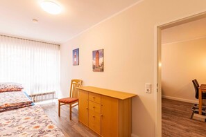 A bedroom with a bed, a desk, a chair, and two paintings on the wall. - Komfortable, Ruhige und Zentral Gelegene Ferienwohnung Seeschwalbe auf Borkum - Strandstraße 5-7 (Borkum)