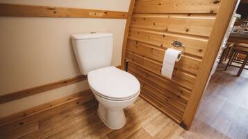Een badkamer met houten lambrisering, een toilet, een houten vloer en een handdoekrek.