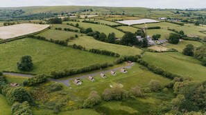 An aerial view of a rural landscape with rolling fields, a few scattered buildings, and a winding road. - Hot Tub Cabin With Views Over The Brecon Beacons (Brecon)