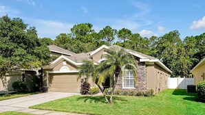 A single-story house with a garage, a well-maintained lawn, and a small tree in the front yard. - 3BR Heated Pool+Spa | Movie Room | Pet-Friendly (Orlando)
