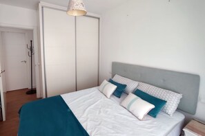Una camera da letto con un letto, una testiera grigia e una porta bianca.