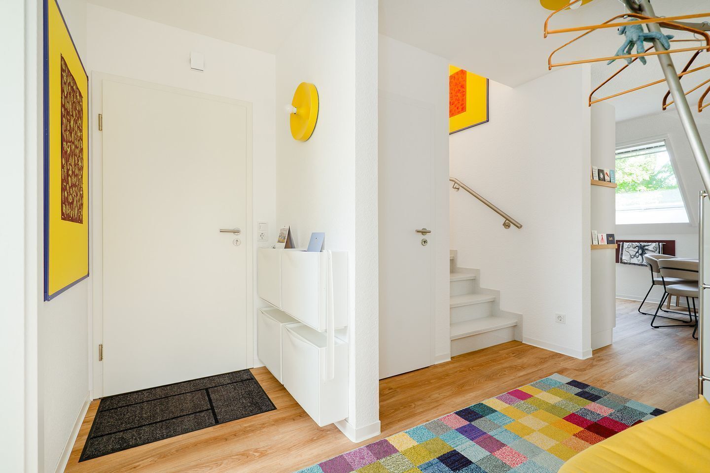 Un interior moderno con una escalera, paredes blancas y una alfombra colorida.