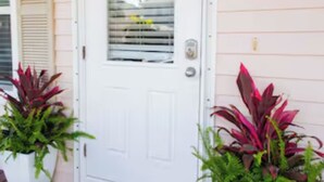 A white door with a window, a green number plate, and two potted plants on a wooden deck. - 3-bedroom townhome in Key West with fitness room, WiFi (Key West)