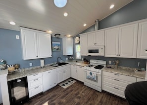 A kitchen with white cabinets, a microwave, a stove, and a dishwasher.