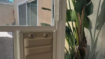 A sliding glass door with a view of a house and a large plant outside.