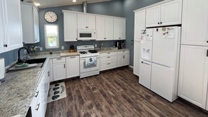 Una cocina moderna con armarios blancos, microondas, cocina a gas y refrigerador.