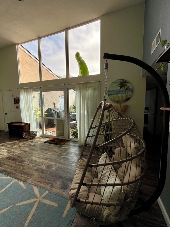 A spacious room with a large window, a hanging chair, and a view of the outdoors.