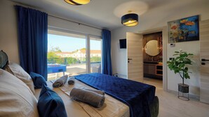 A modern hotel room with a bed, a large window, a view of the outside, and a bathroom with a mirror and sink. - Villa BAVIGO (Istria - Marcana) (Marcana)