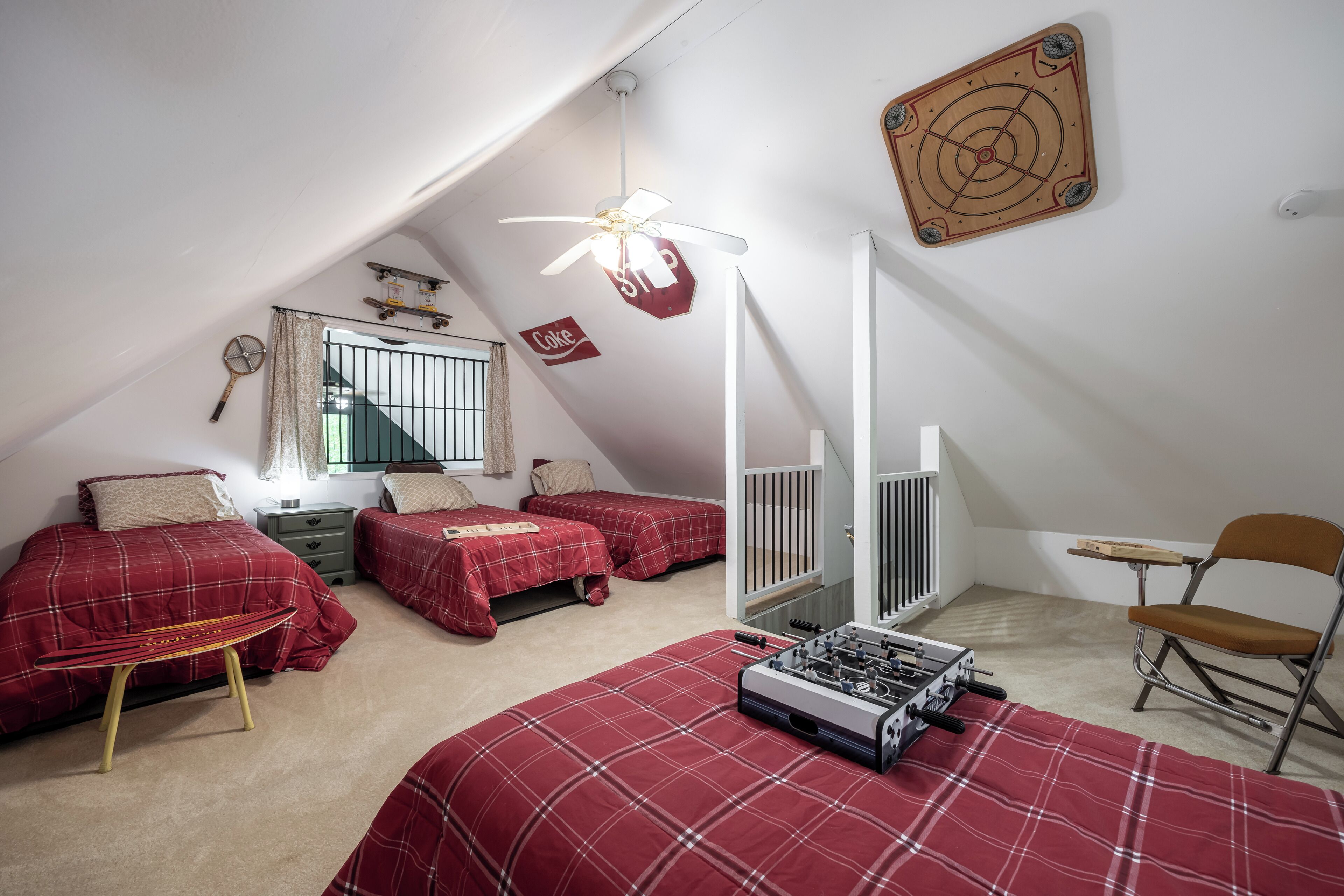 Un dormitorio con dos camas, un ventilador de techo, un escritorio, una silla y una ventana.