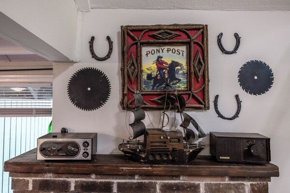A fireplace mantel with vintage radios and a framed poster of a cowboy on horseback. - Charming 2-bedroom cottage in lovely Madison with WiFi, AC (Madison)