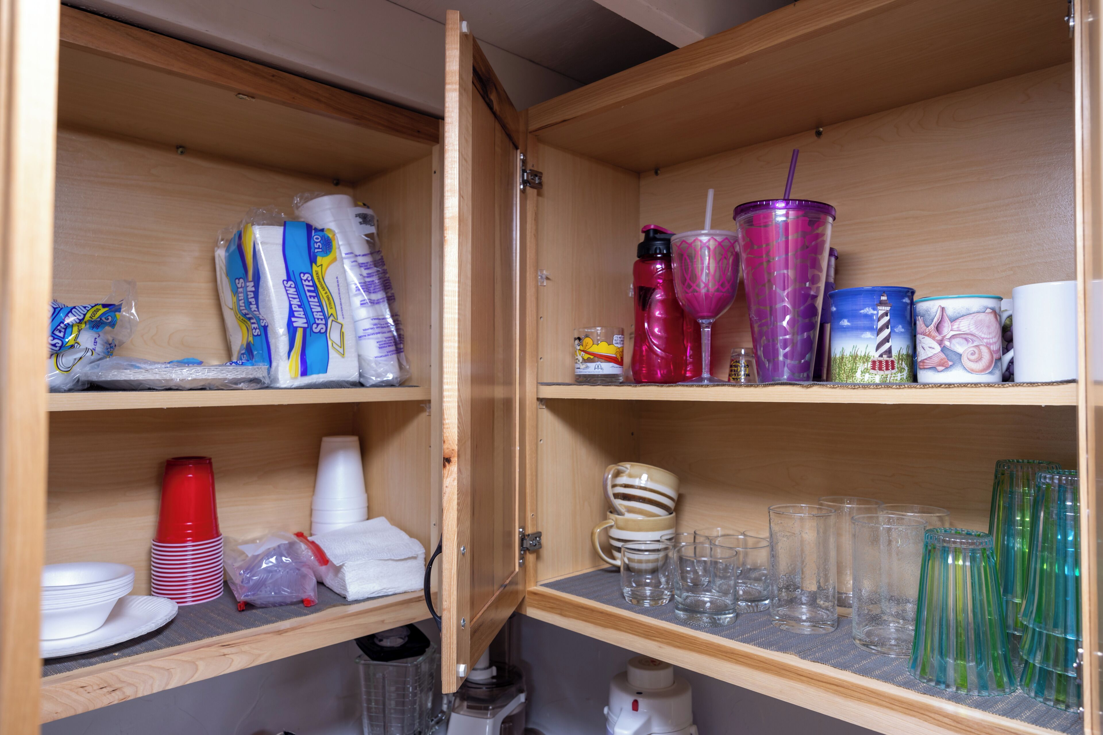A kitchen with wooden cabinets, containing various kitchenware and utensils.