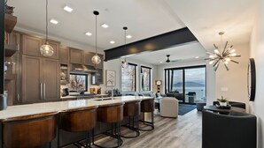 A modern kitchen with a central island, bar stools, and pendant lighting. - Waterfront Luxe Seasons ~8~ Boat Slip (Sandpoint)