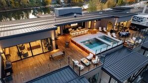 A modern multi-story building with a rooftop deck featuring a pool, outdoor seating, and a bar area. - Waterfront Luxe Seasons ~8~ Boat Slip (Sandpoint)