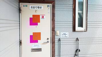 Una puerta con el logotipo de PayPay, una ventana y un estante metálico con un paraguas.