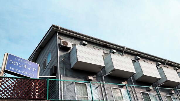 A building with multiple balconies, air conditioning units, and a signboard. - Hotel Frontier (Isinomaki)