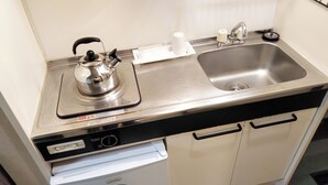 A compact kitchenette with a stainless steel sink, a kettle, and a dishwasher. - Hotel Frontier (Isinomaki)