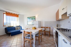 Een koelkast, een oven, een kookplaat, kookgerei, borden en bestek